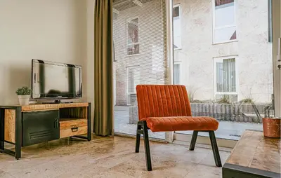 an orange chair in a room with a television at Sea Bass in Egmond aan Zee
