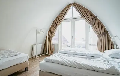 a bedroom with two beds and a large window at Flat Fish in Egmond aan Zee