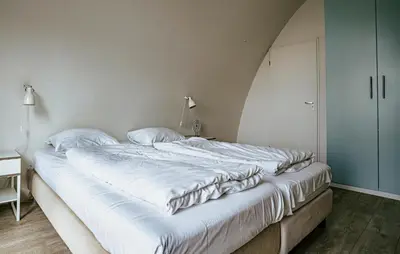 a large white bed in a room with a desk at Flat Fish in Egmond aan Zee