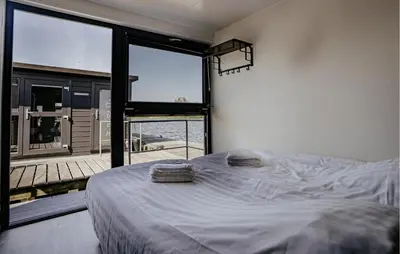 a bedroom with a bed and a large window at Havenlodge Plus in Uitgeest