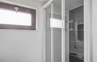 a glass shower door with a window in a bathroom at Havenlodge Plus in Uitgeest