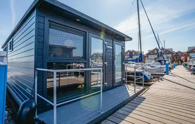 a small building on a dock next to boats at Havenlodge Plus in Uitgeest