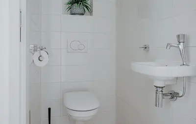 a white bathroom with a toilet and a sink at Lobster in Egmond aan Zee