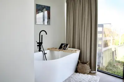 a white bath tub in a room with a window at Studio in Amsterdam Area Horizon Hideaway in Broek in Waterland