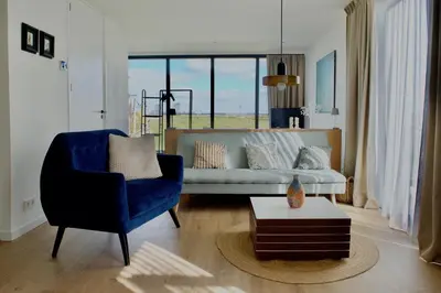 a living room with a blue chair and a couch at Studio in Amsterdam Area Horizon Hideaway in Broek in Waterland