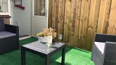 a patio with a table and chairs and a fence at Vakantiehuisje aan Zee - 100m van Strand in Egmond aan Zee