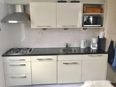 a kitchen with white cabinets and a sink at Vakantiehuisje aan Zee - 100m van Strand in Egmond aan Zee