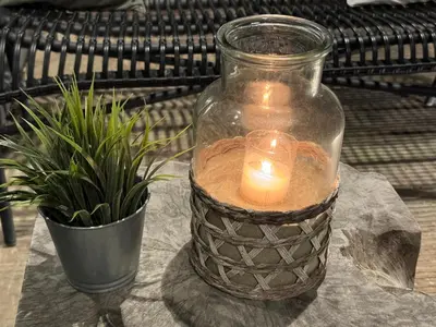 a candle in a glass jar next to a potted plant at Vakantiehuisje aan Zee - 100m van Strand in Egmond aan Zee
