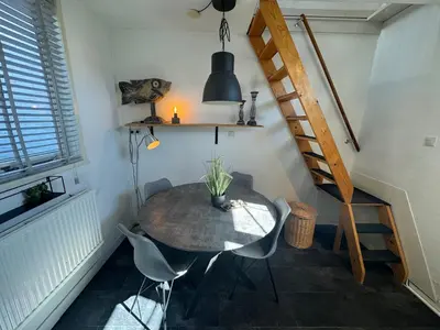 a dining room with a table and chairs and a staircase at Vakantiehuisje aan Zee - 100m van Strand in Egmond aan Zee