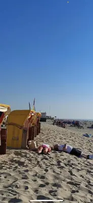 two people laying on the sand on the beach at Vakantiehuisje aan Zee - 100m van Strand in Egmond aan Zee