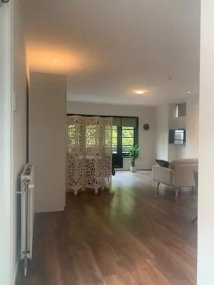 a living room with wooden floors and white walls at B&B aan de Gracht in Alkmaar