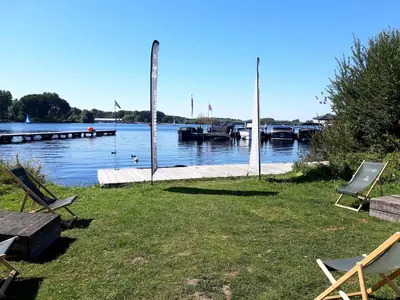 a couple of chairs sitting on the grass next to a dock at Motorjacht At Ease in Amsterdam