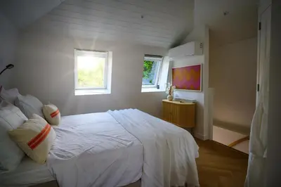 a bedroom with a white bed and two windows at 5 O Clock Somewhere in Bergen