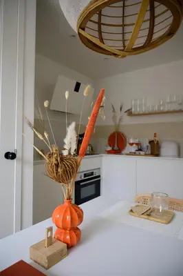 an orange vase with carrots on a counter in a kitchen at 5 O Clock Somewhere in Bergen