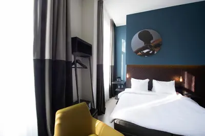 a hotel room with a bed and a yellow chair at Boutique Hotel Oosteinde in Amsterdam