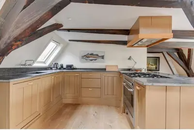 a kitchen with wooden cabinets and a stove top oven at Hoogwaardig afgewerkt loft in oude stadscentrum in Alkmaar