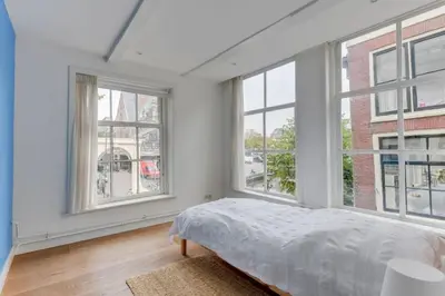 a bedroom with white walls and windows and a bed at Hoogwaardig afgewerkt loft in oude stadscentrum in Alkmaar