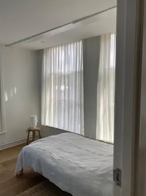 a bedroom with a bed and two large windows at Hoogwaardig afgewerkt loft in oude stadscentrum in Alkmaar