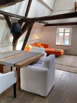 a living room with a wooden table and white chairs at Hoogwaardig afgewerkt loft in oude stadscentrum in Alkmaar