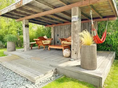 a wooden deck with a hammock and chairs on it at Bungalow 77 op Recreatiepark De Wielen in Sint Maarten