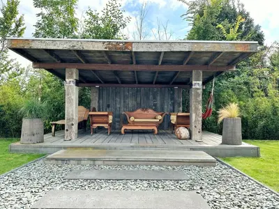 a wooden gazebo with a couch under it at Bungalow 77 op Recreatiepark De Wielen in Sint Maarten