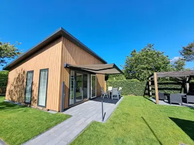 a house with a deck and an umbrella at Have a nice stay! - Vakantiehuis Buitenplaats in Noordwijkerhout