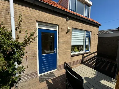 a blue door on a brick house with a bench at Vakantiewoning Zon, Zee & Duin - Egmond aan Zee in Egmond aan Zee