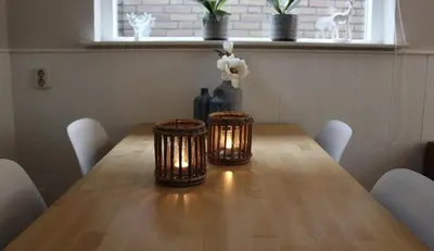 a dining room table with candles and a vase with flowers at Vakantiewoning Zon, Zee & Duin - Egmond aan Zee in Egmond aan Zee