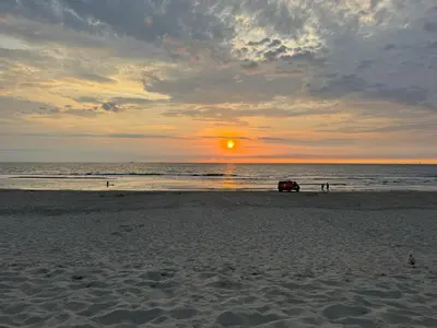 a car parked on the beach at sunset at Vakantiewoning Zon, Zee & Duin - Egmond aan Zee in Egmond aan Zee