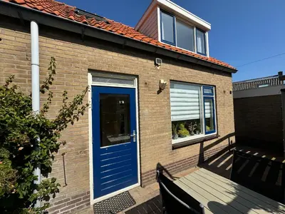 a blue door on a brick house with a bench at Vakantiewoning Zon, Zee & Duin - Egmond aan Zee in Egmond aan Zee