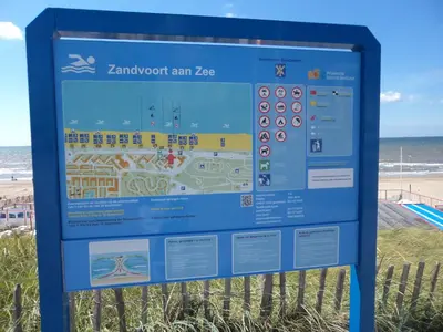 a sign at the beach with the ocean in the background at Appartement 't Zomerhuis in Zandvoort