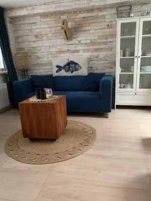 a living room with a blue couch and a coffee table at Appartement 't Zomerhuis in Zandvoort