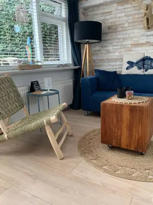 a living room with a blue couch and a table at Appartement 't Zomerhuis in Zandvoort