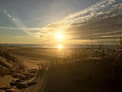 a sunset on a beach with the sun setting at Relax Cozy Dirkshorn Stay in Dirkshorn