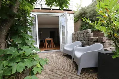 a patio with two white chairs and a table at DUINUNDER In de duinen, loopafstand naar 't strand in Noordwijk aan Zee