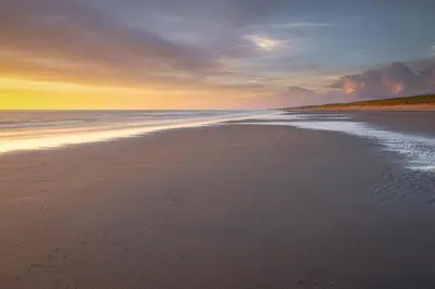 a beach with the tide coming in at sunset at DUINUNDER In de duinen, loopafstand naar 't strand in Noordwijk aan Zee