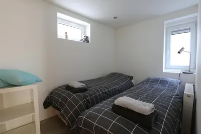 two twin beds in a room with two windows at DUINUNDER In de duinen, loopafstand naar 't strand in Noordwijk aan Zee
