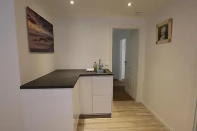a kitchen with white cabinets and a black counter top at DUINUNDER In de duinen, loopafstand naar 't strand in Noordwijk aan Zee