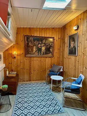 a room with wooden walls with a painting and two chairs at Houseboat De Cornelia in Amsterdam