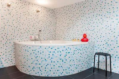 a bathroom with a tub in a blue tiled wall at Houseboat De Cornelia in Amsterdam