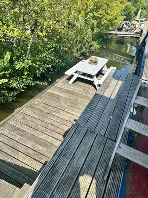 a wooden dock with a picnic table on the water at Houseboat De Cornelia in Amsterdam