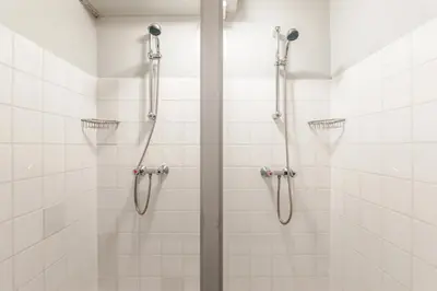 a shower in a bathroom with white tiles at Houseboat De Cornelia in Amsterdam
