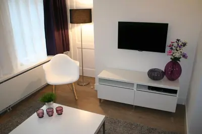 a white living room with a tv and a white chair at Rosies Place in Amsterdam