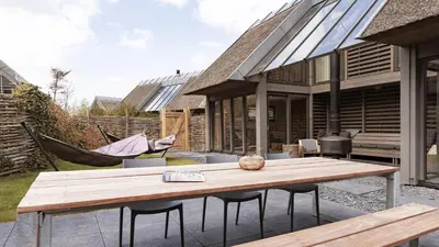 a patio with a wooden table and a hammock at Dutchen Duynvoet Suites in Schoorl