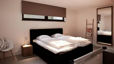 a bedroom with a bed with white sheets and a mirror at Dutchen Duynvoet Suites in Schoorl