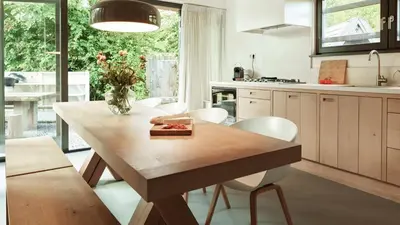a kitchen with a wooden table and white chairs at Dutchen Duynvoet Suites in Schoorl