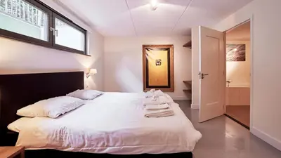 a bedroom with a bed with white sheets and a window at Dutchen Duynvoet Suites in Schoorl