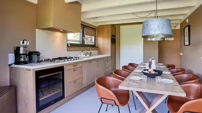 a kitchen with a long table and leather chairs at Dutchen Duynvoet Suites in Schoorl