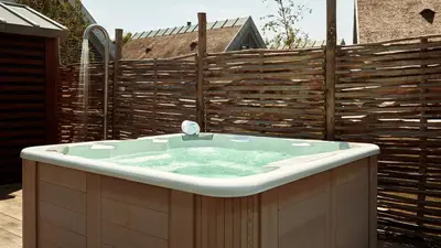 a bath tub in front of a wooden fence at Dutchen Duynvoet Suites in Schoorl