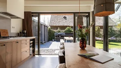 a kitchen with a table with a vase of flowers on it at Dutchen Duynvoet Suites in Schoorl